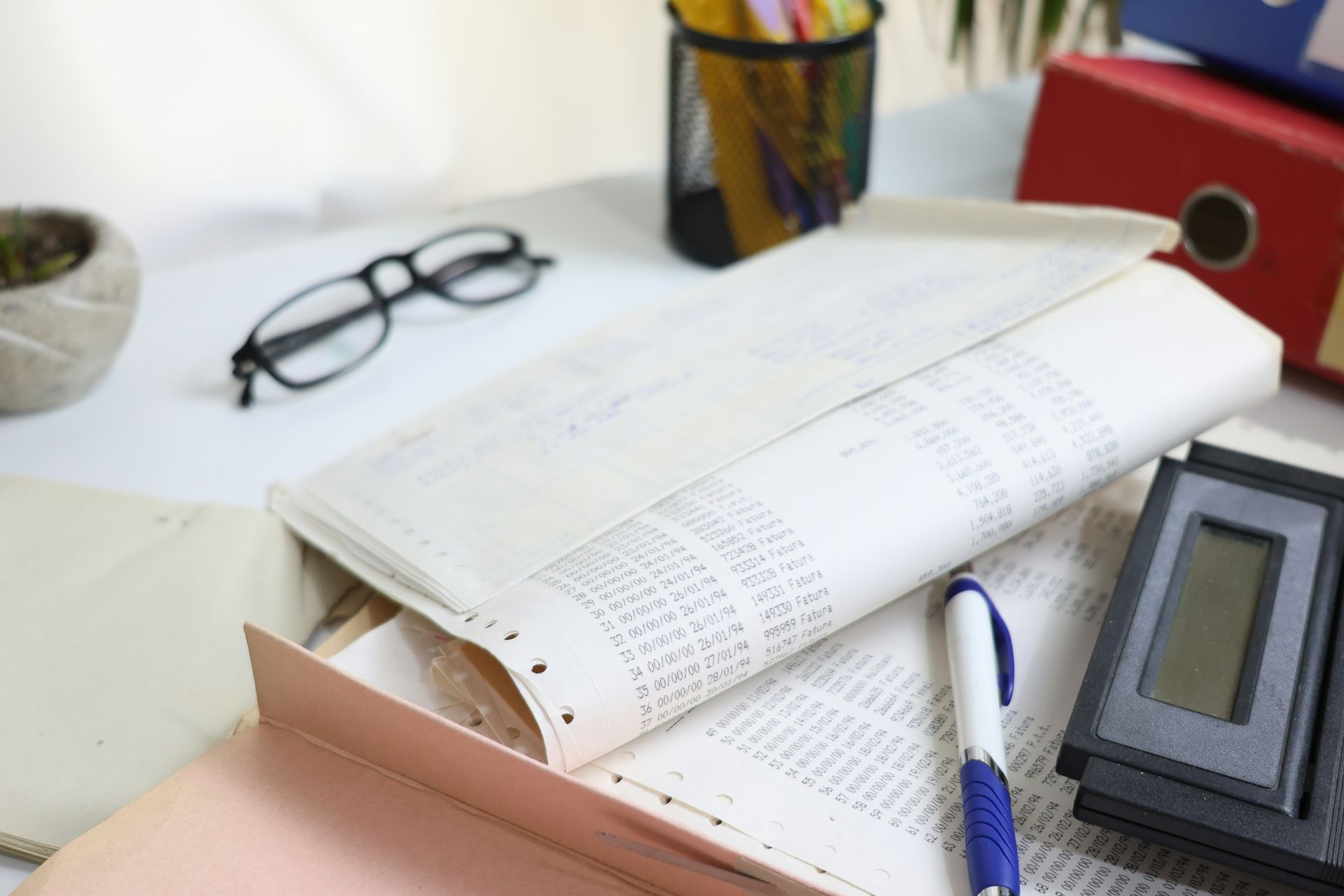 Desk with papers, glasses, calculator, and office supplies